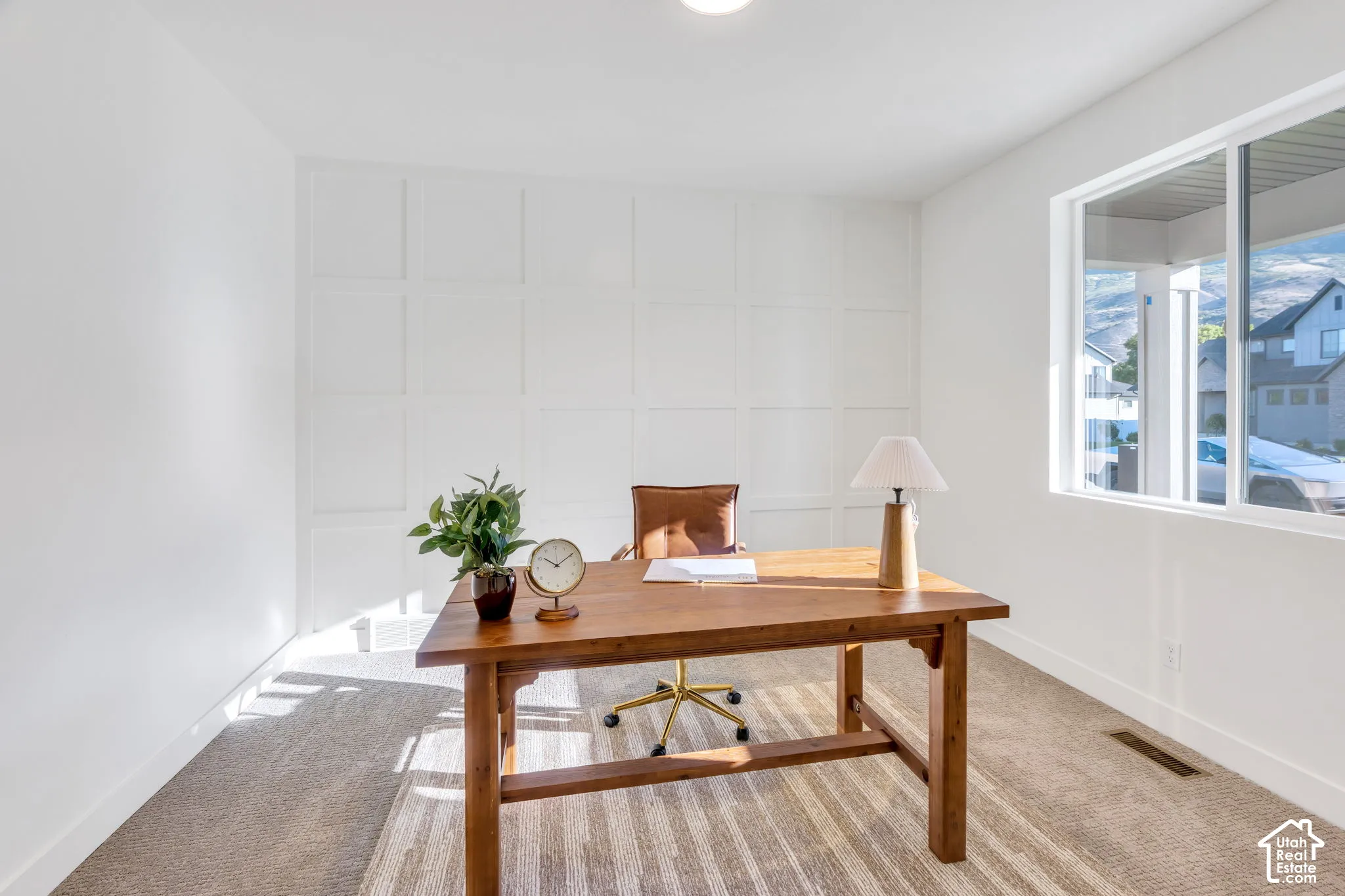 White wall paneling, large window, neutral carpeting, recessed ceiling light