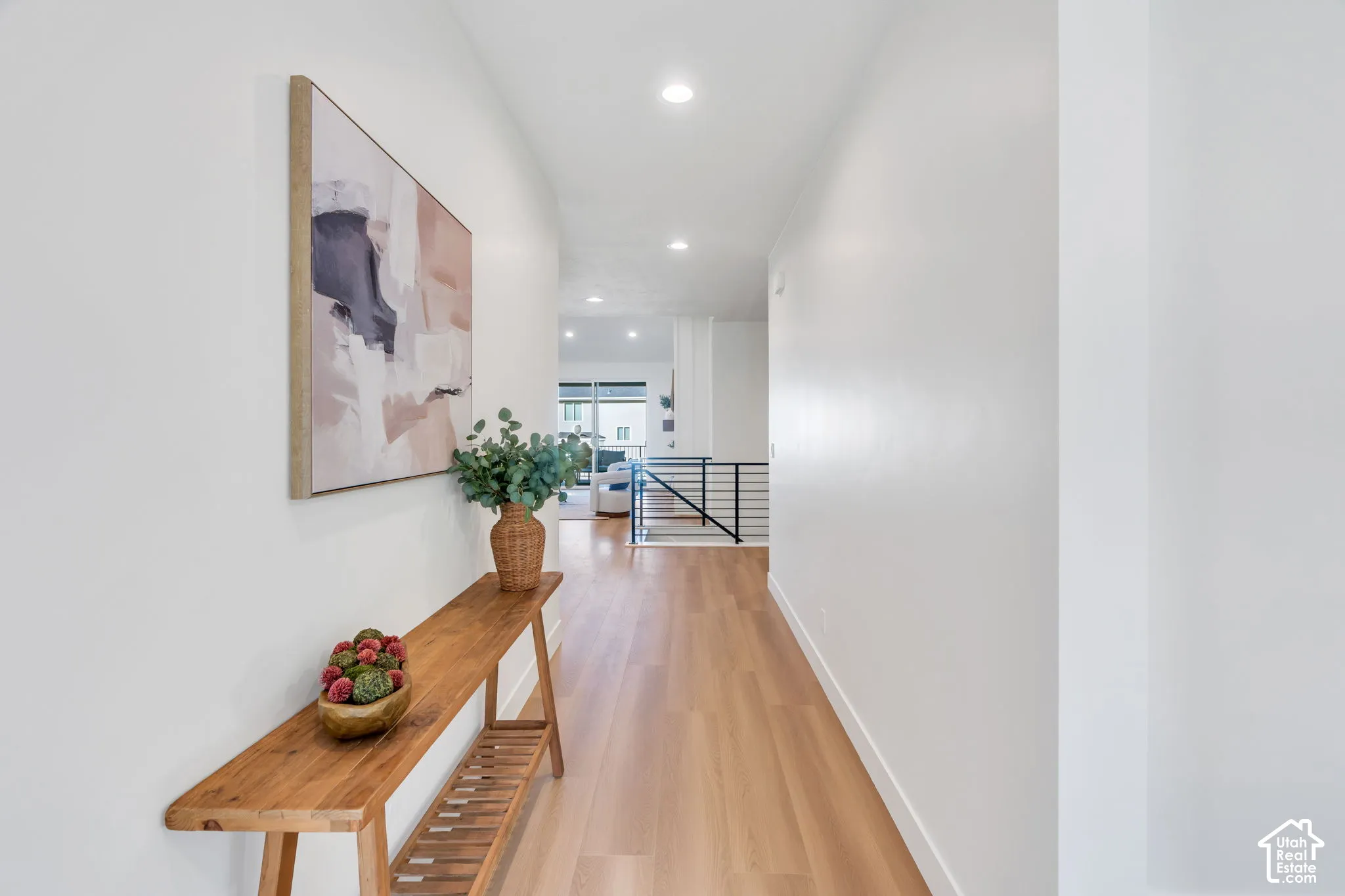 Recessed lighting illuminates the hall with wood-finish flooring