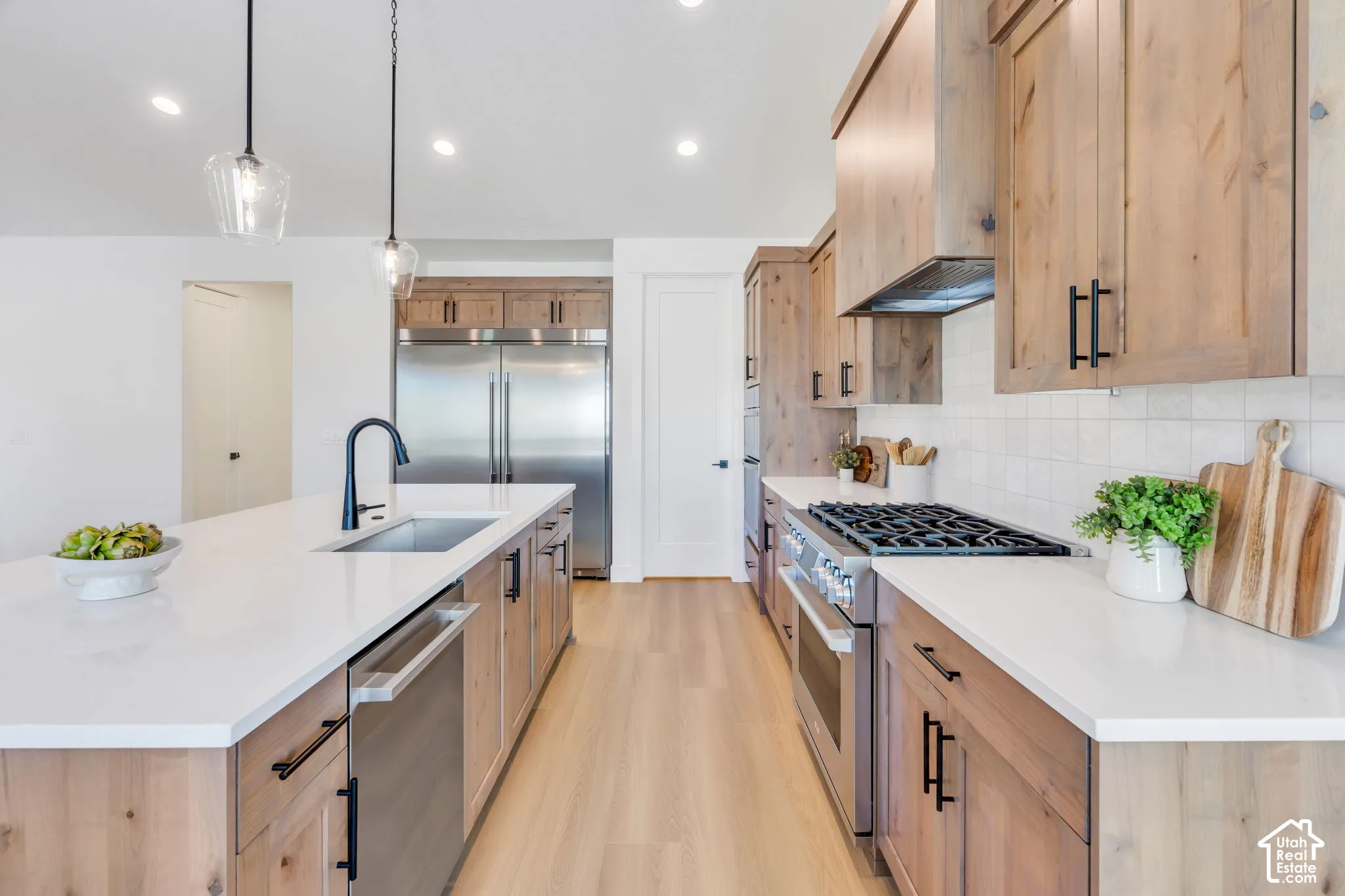 Spacious kitchen featuring wood-finish cabinetry, white countertops, stainless steel appliances, and wood-finish flooring