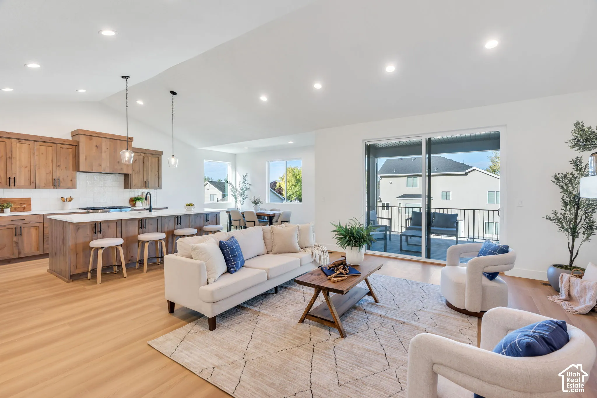 Vaulted ceilings, recessed lighting, wood-finish flooring, sliding glass doors, and a kitchen island with seating