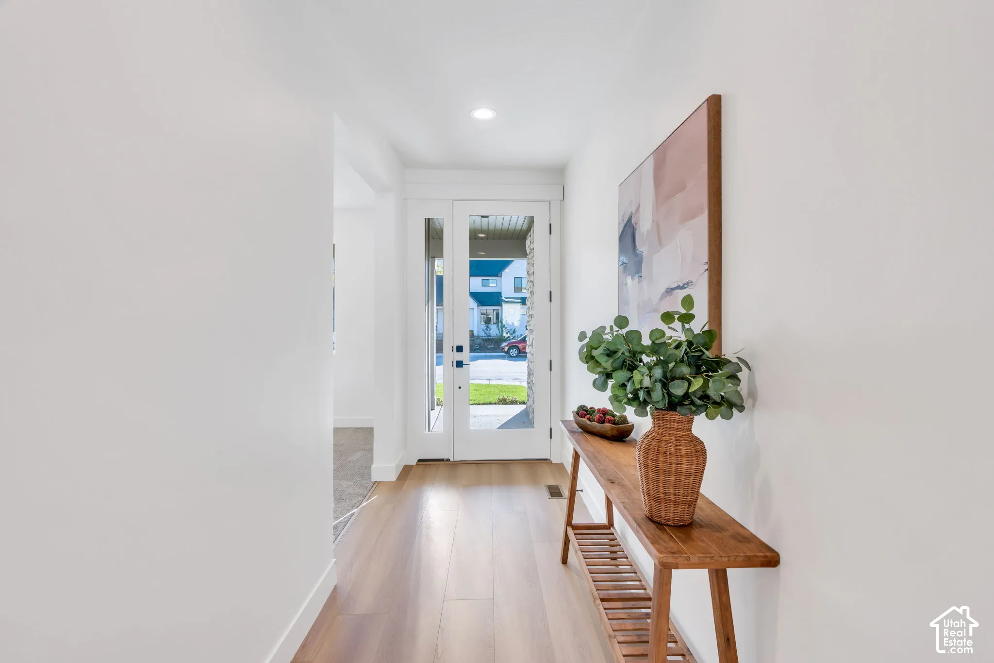 Wood-finish flooring, recessed lighting, and a white entry door with glass panels