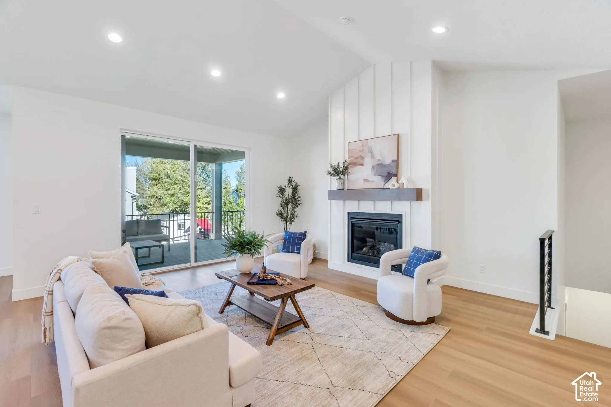Vaulted ceiling, recessed lighting, wood-finish flooring, fireplace with shiplap-style surround and wood mantle, and sliding glass door to exterior