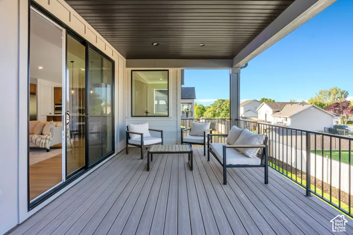 Covered outdoor patio featuring composite decking, black metal railings, and a large sliding glass door