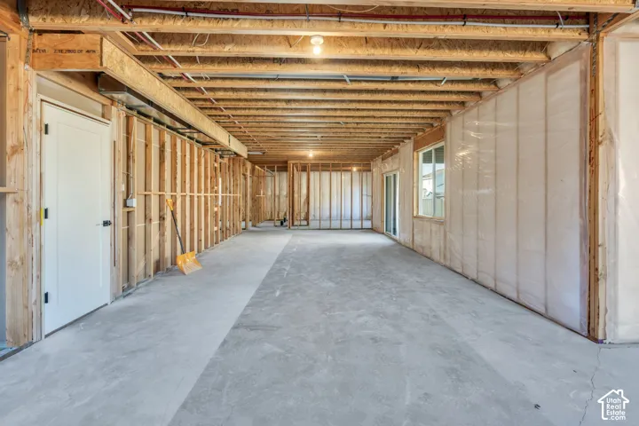 Unfinished basement featuring exposed wood framing, concrete flooring, and an egress window