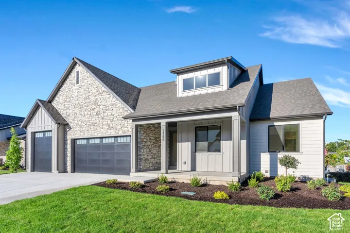Stone and siding exterior with a covered entry, multiple rooflines, and a two-car garage