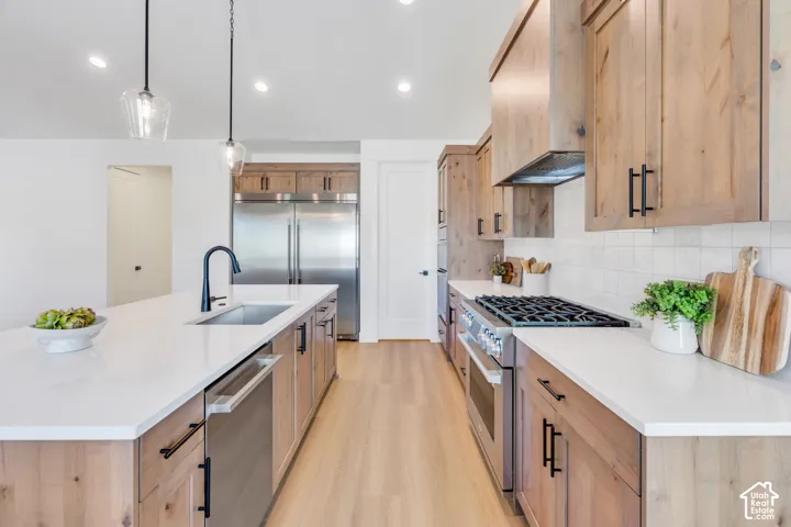 Spacious kitchen featuring wood-finish cabinetry, white countertops, stainless steel appliances, and wood-finish flooring