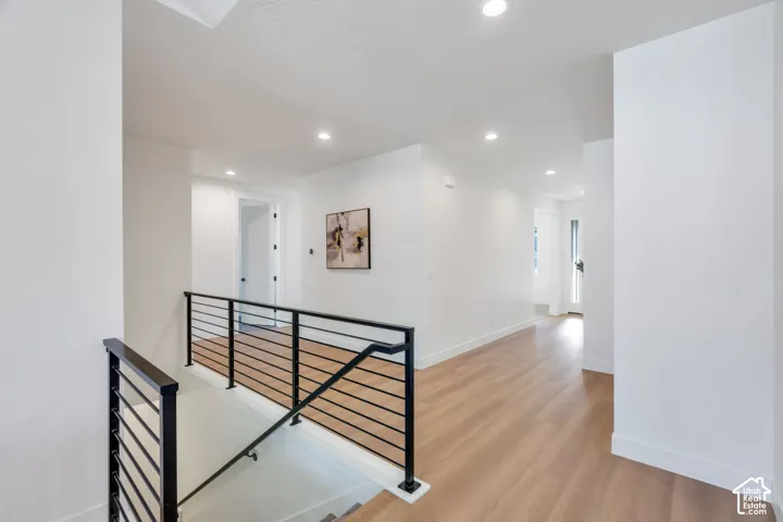 Modern black metal horizontal bar railing with wood-finish flooring, recessed lighting, and crisp white walls