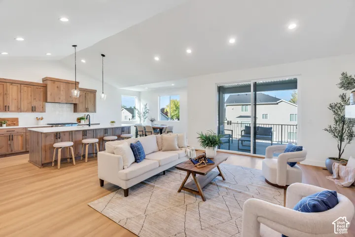 Vaulted ceilings, recessed lighting, wood-finish flooring, sliding glass doors, and a kitchen island with seating