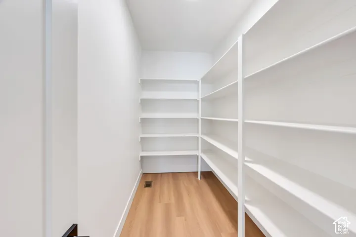 Walk-in pantry with extensive built-in white shelving and wood-finish flooring