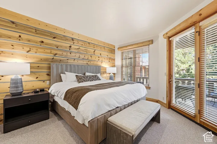 Wood-paneled accent wall, neutral carpeting, and a glass-paneled door with a wood frame