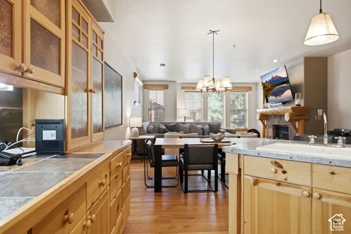 Open-concept living area with wood-finish flooring, a stone-tiled fireplace, and a wood mantel