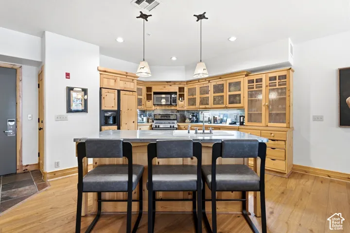 Kitchen featuring a center island, wood-finish flooring, custom wood cabinetry, stainless steel appliances, and recessed lighting