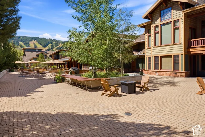 Expansive brick paver patio featuring a stone-clad building exterior with wood siding and large windows
