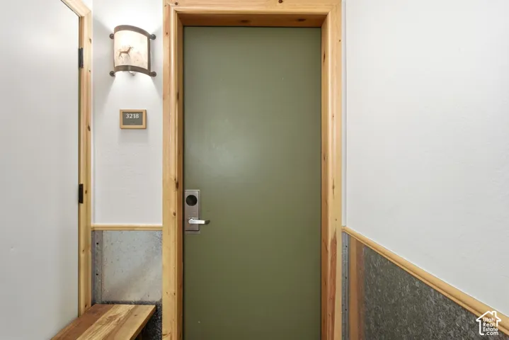 Entryway featuring a solid door, natural wood trim, metal wainscoting, and a built-in wood bench