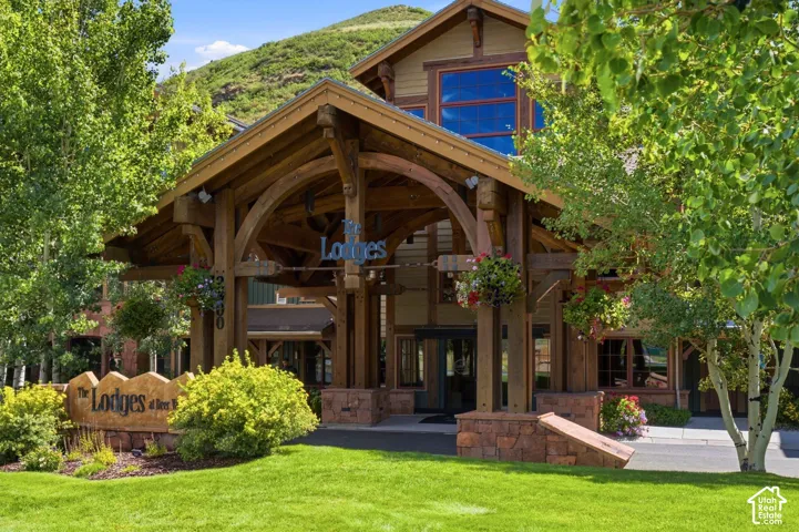 Timber frame portico entrance with stone bases, visible signage, and a mountain backdrop