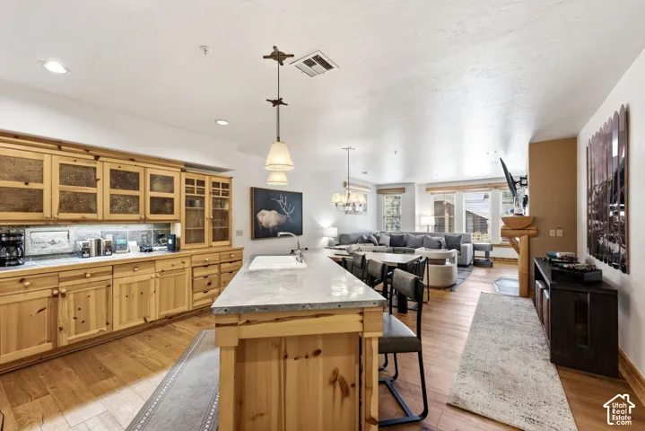 Open-concept living area with wood-finish flooring, recessed lighting, and a prominent kitchen island with seating