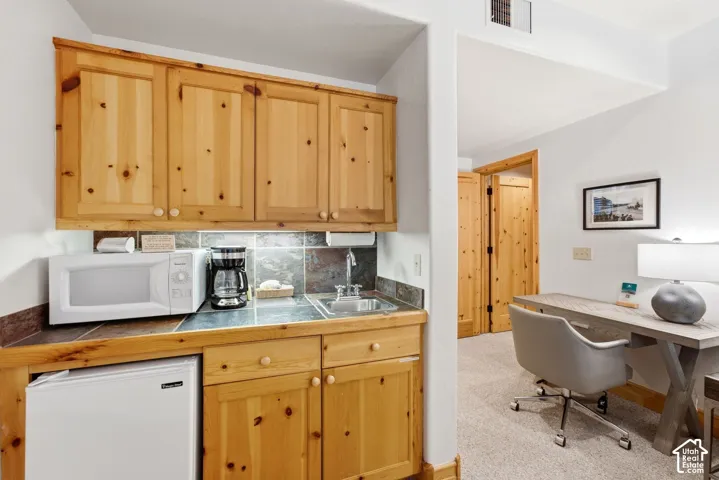 Built-in kitchenette featuring wood cabinetry, stone-finish countertops, and a stainless steel sink