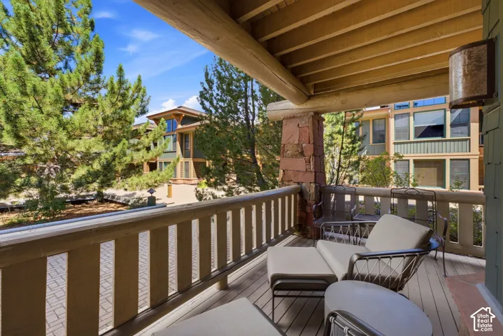 Covered outdoor deck with a wood plank surface and log beam ceiling