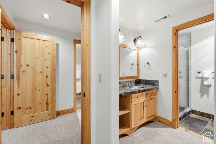 Full bathroom with a wood-finish vanity, integrated sink, and an enclosed shower