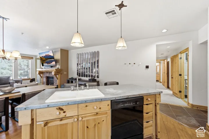 Kitchen island with integrated dishwasher, dual pendant lighting, and a white basin sink