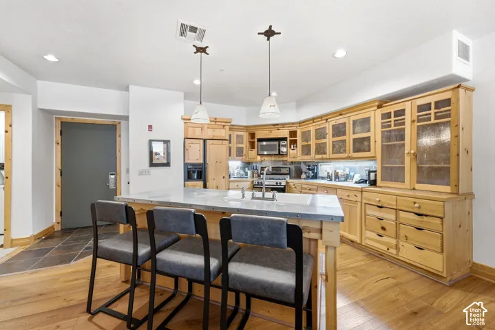 Kitchen featuring wood-finish cabinetry, stainless steel appliances, a center island with a light-toned countertop, and recessed lighting