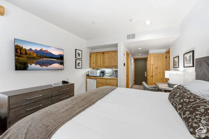 Integrated kitchenette featuring wood cabinetry and a stainless steel sink