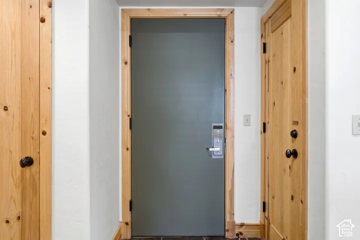 Gray door with wood trim, wood-paneled door with dark hardware, white wall finish, and light switches