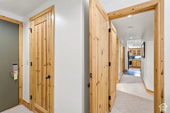 Hallway featuring light wood-finish doors and trim, neutral carpeting, and recessed lighting