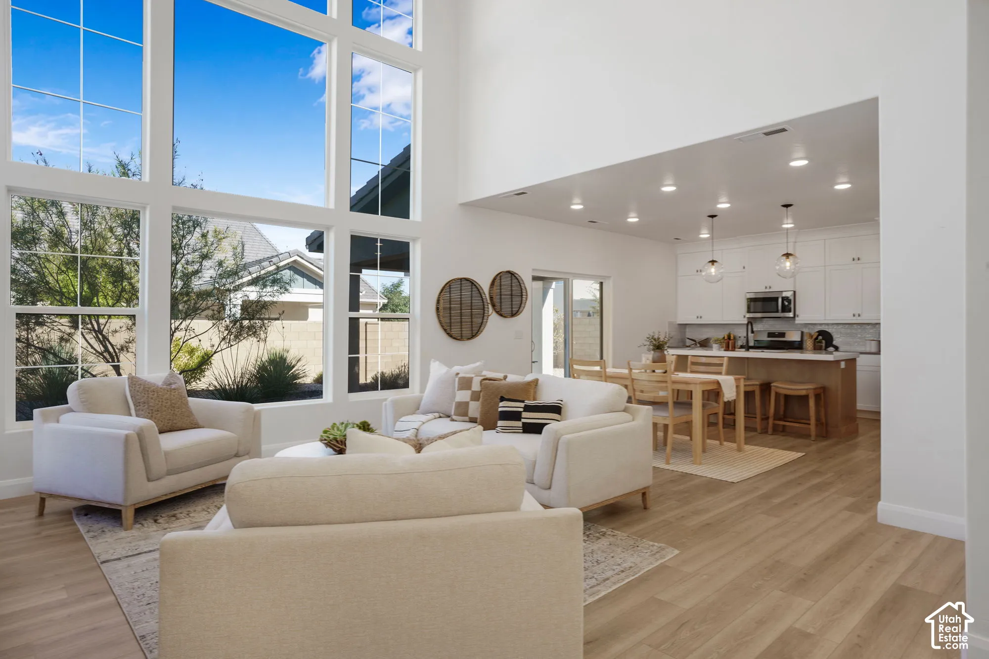 High ceilings, expansive windows, wood-finish flooring, white cabinetry, and recessed lighting