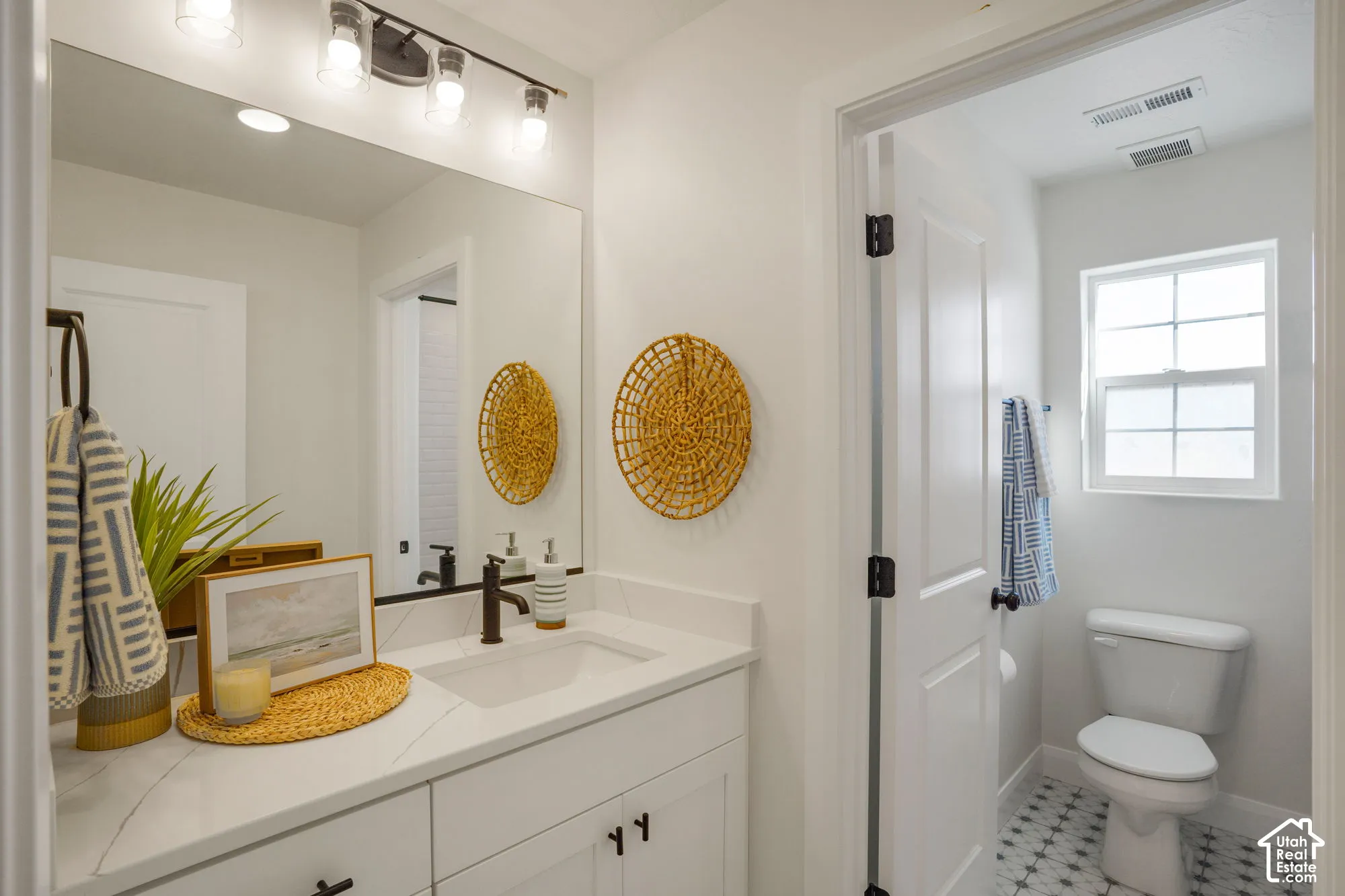White vanity with a quartz countertop, an undermount sink, and a matte black faucet