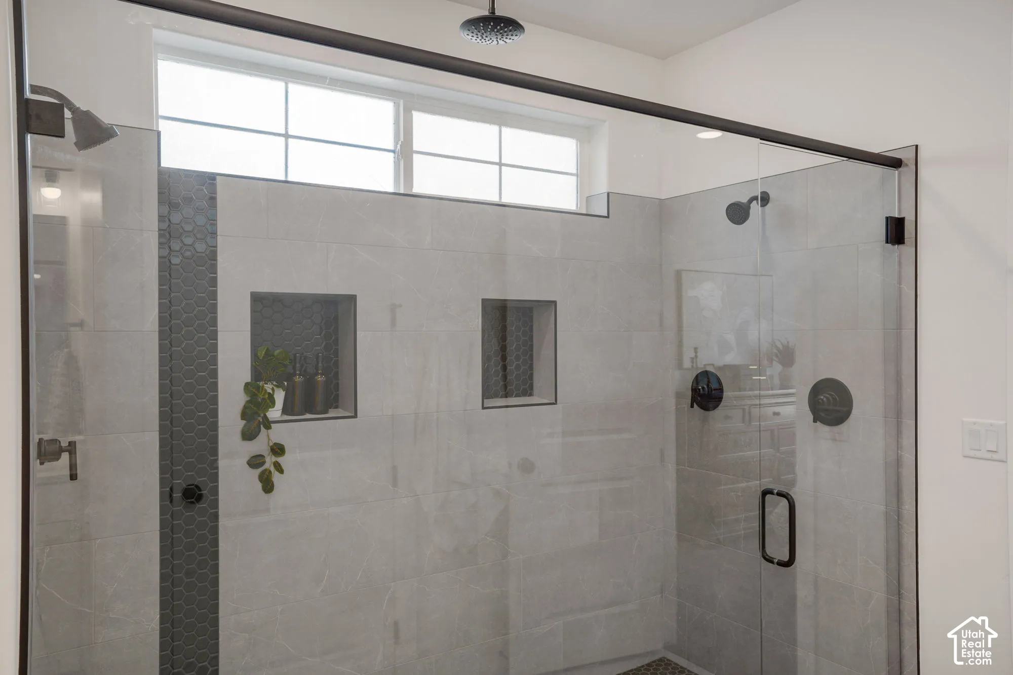 Glass-enclosed shower with a matte black overhead rain shower and separate showerhead