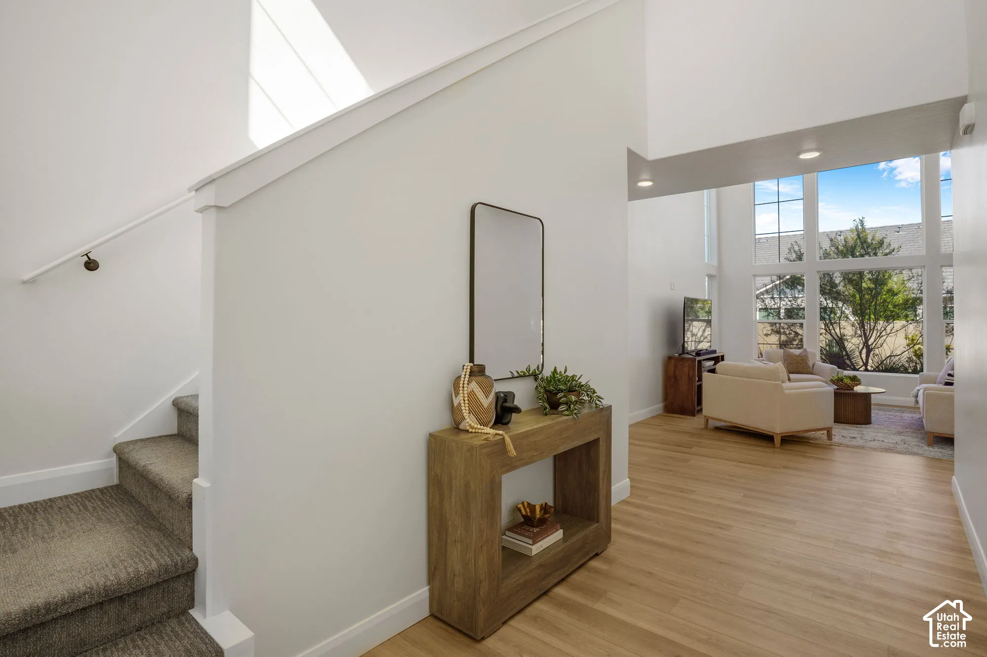Wood-finish flooring, staircase with carpeted treads, white walls, large multi-pane windows, and recessed lighting