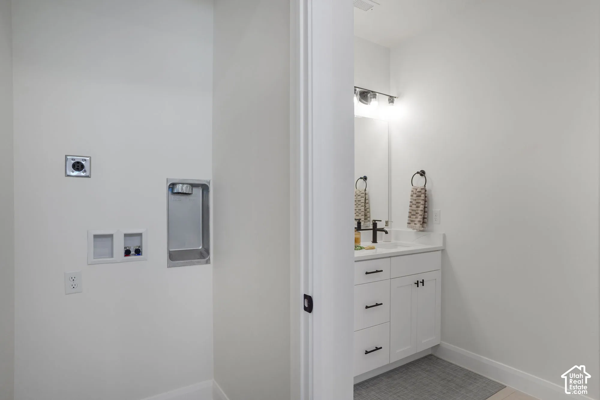White shaker-style vanity with a white countertop and matte black hardware
