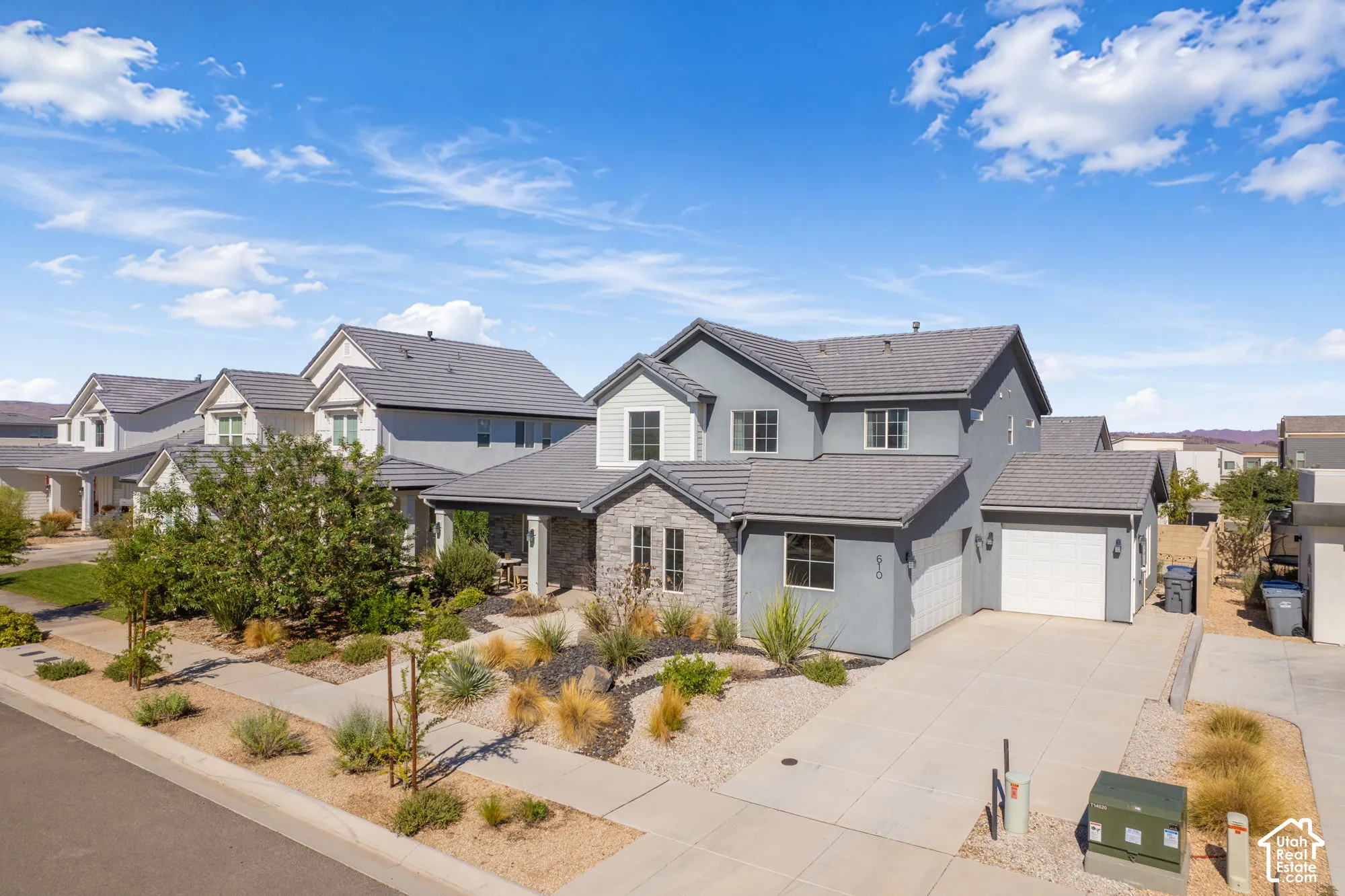 Modern two-story residence with a gray stucco exterior and stone facade accents