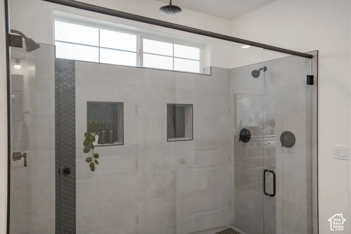 Glass-enclosed shower with a matte black overhead rain shower and separate showerhead