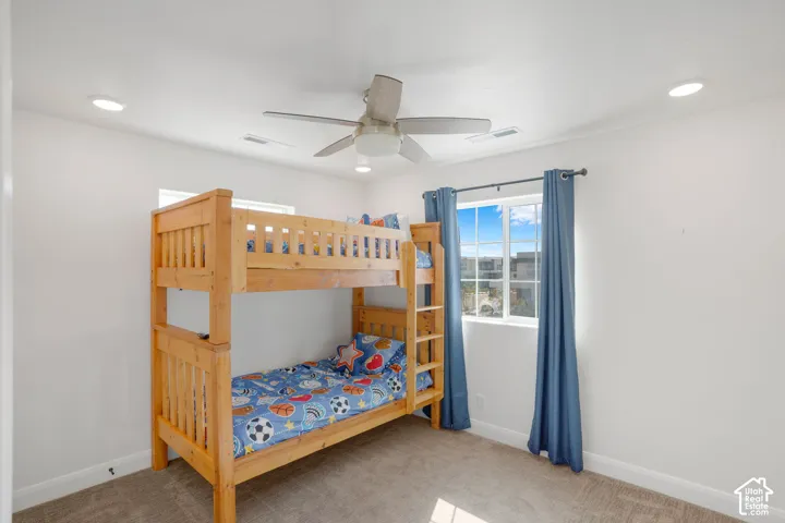 Recessed lighting, ceiling fan, white walls, carpeted flooring, and a window with natural light