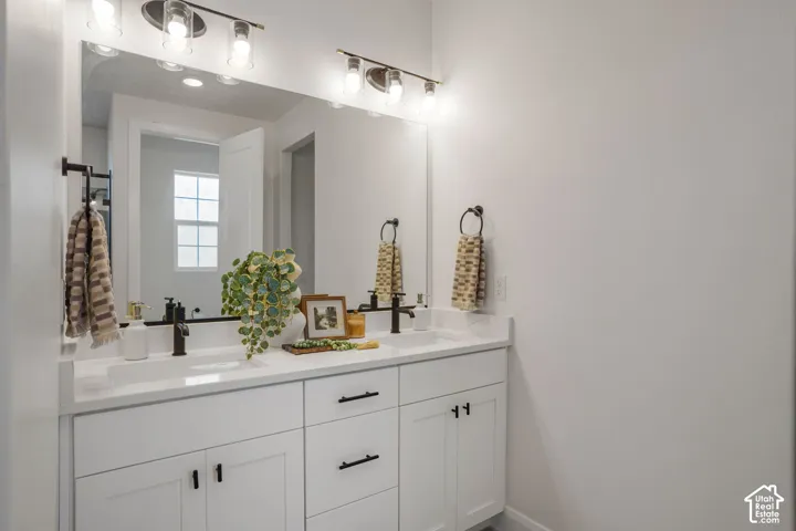 Dual vanity with white cabinetry and integrated sinks, matte black fixtures, and overhead bar lighting