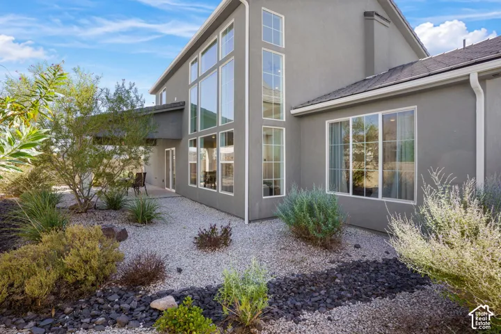 Stucco exterior with multiple large windows, a covered patio, and a gravel and rock landscaped area