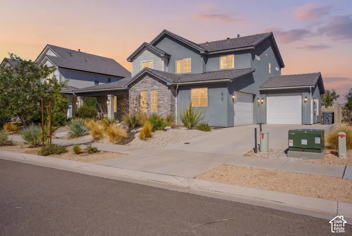 Contemporary two-story residence with a stucco and stone facade, featuring a prominent two-car garage and a single-car garage