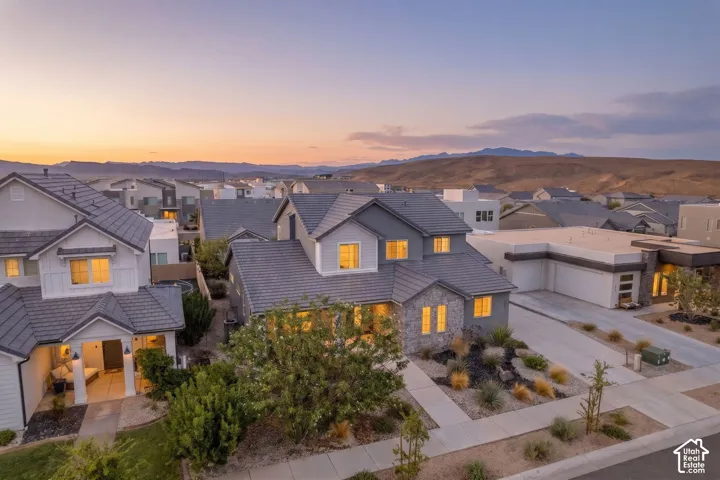 Two-story residence featuring a covered front entry, stone and siding exterior, a two-car garage, and landscaped front yard with desert-adapted plantings