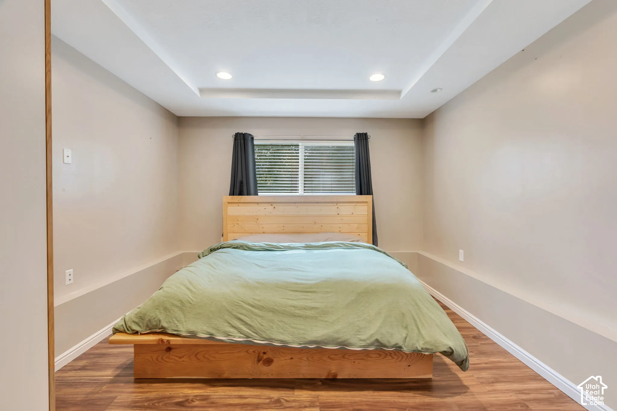 Recessed lighting, tray ceiling, wood-finish flooring, and a window with blinds