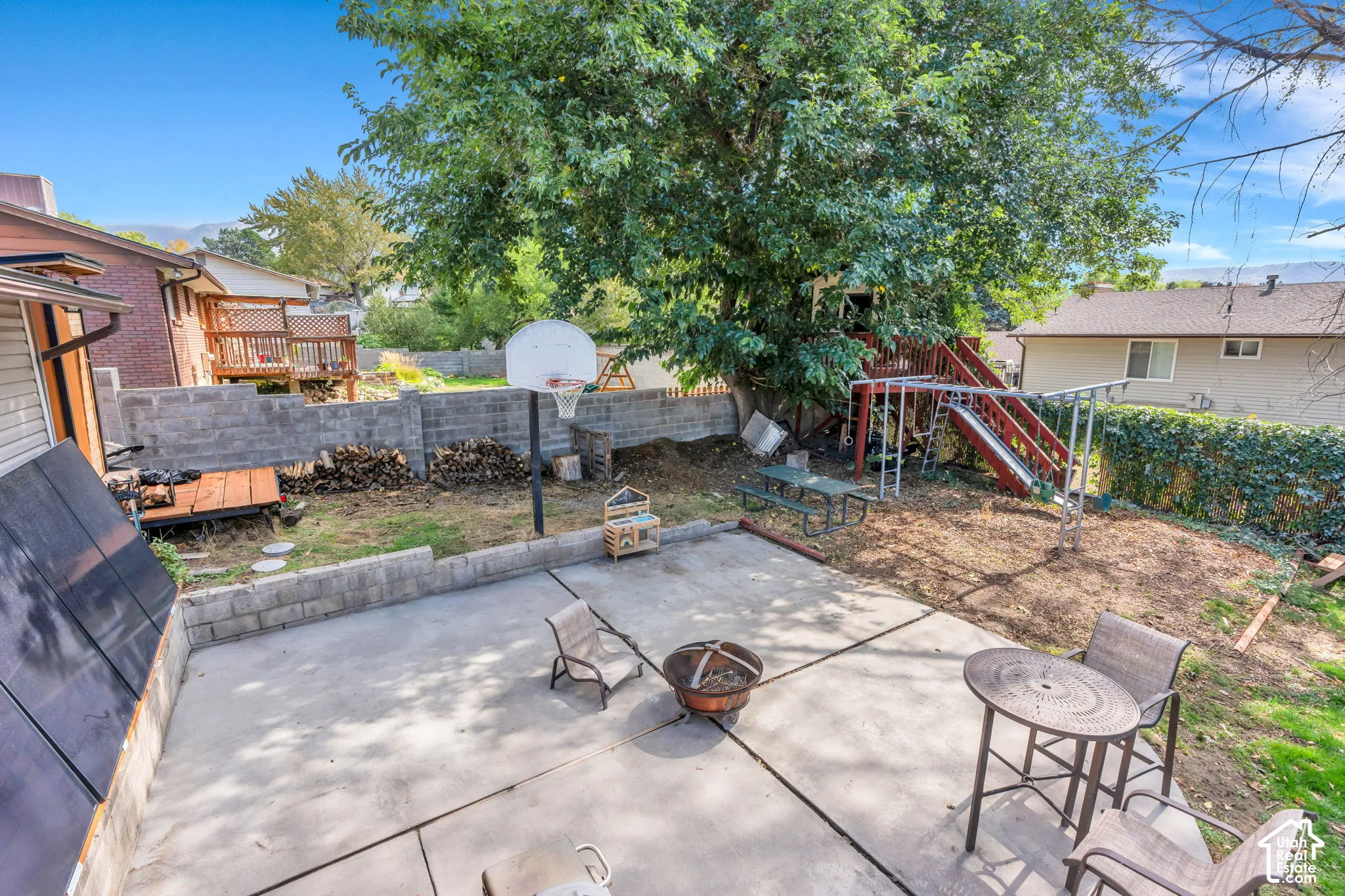 Patio space with concrete surfacing, surrounding retaining walls, and mature trees
