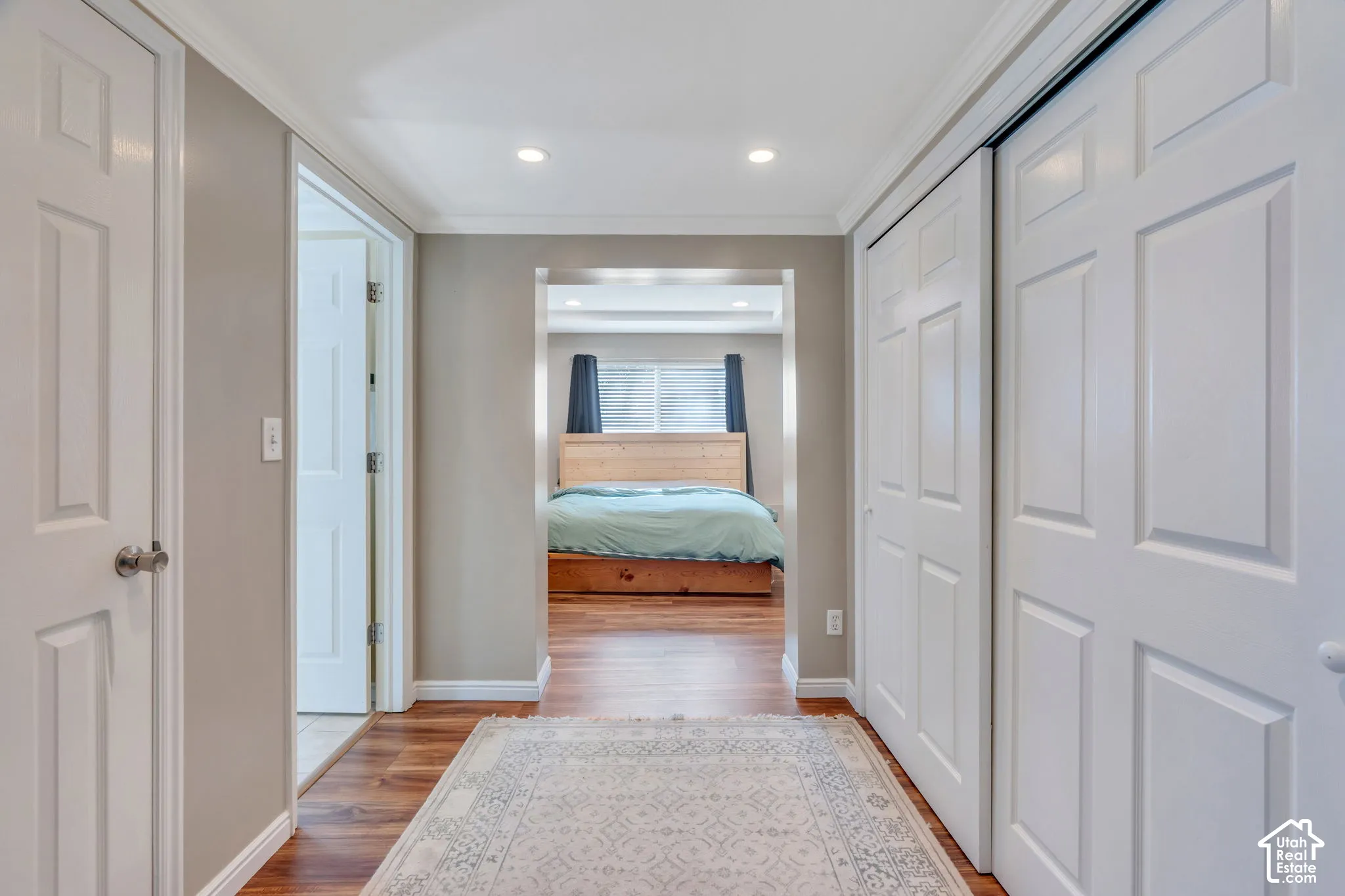 Hallway featuring wood-finish flooring, recessed lighting, white paneled doors, and crown molding