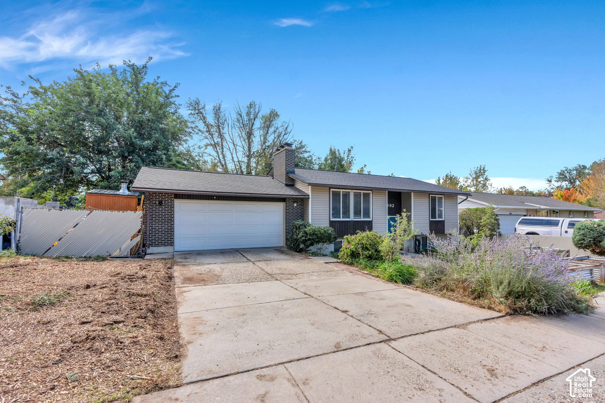Split-level residence featuring a two-car garage, brick facade detailing, and a concrete driveway
