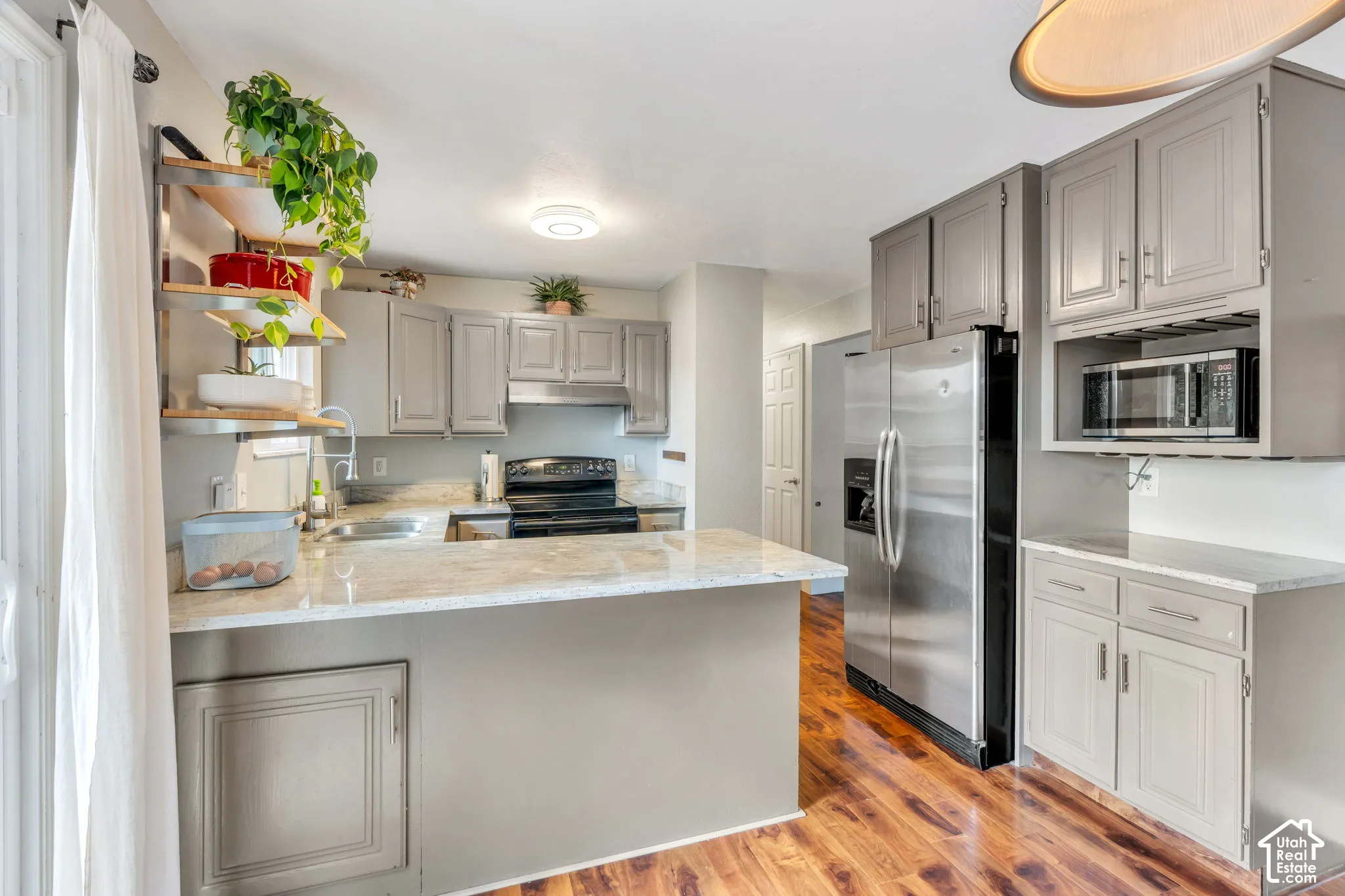 Kitchen featuring light gray cabinetry, stainless steel appliances, light-toned countertops, and wood-finish flooring