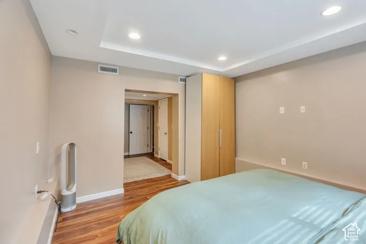 Wood-finish flooring with a neutral wall color, recessed ceiling lighting, and a built-in light wood-tone wardrobe