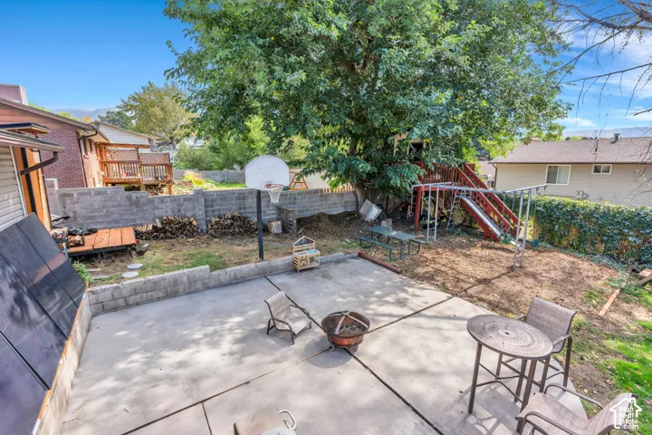 Patio space with concrete surfacing, surrounding retaining walls, and mature trees