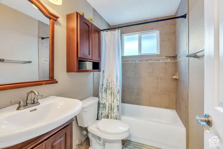 Bathroom featuring a vanity with an integrated sink, a framed mirror, a built-in medicine cabinet, a toilet, and a combination tub/shower with tiled surround