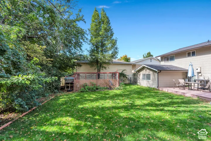 Expansive backyard featuring a green lawn, established perimeter trees, a paved patio, and a detached shed