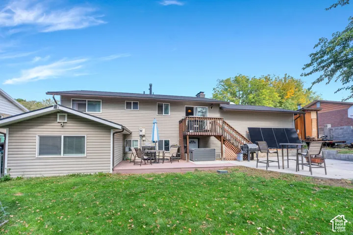 Two-story residence with light-colored siding, a multi-level deck, and a grass lawn